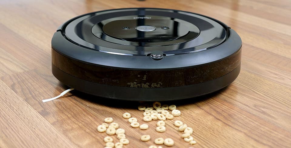 Roomba e5 cleaning cereal on hardwood floor