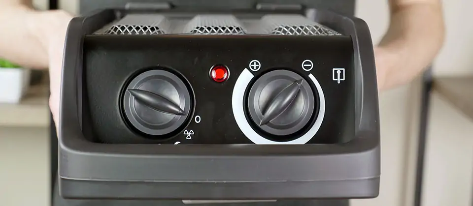 The top of the Tenergy space heater contains two knobs, a handle, and a heat indicator light